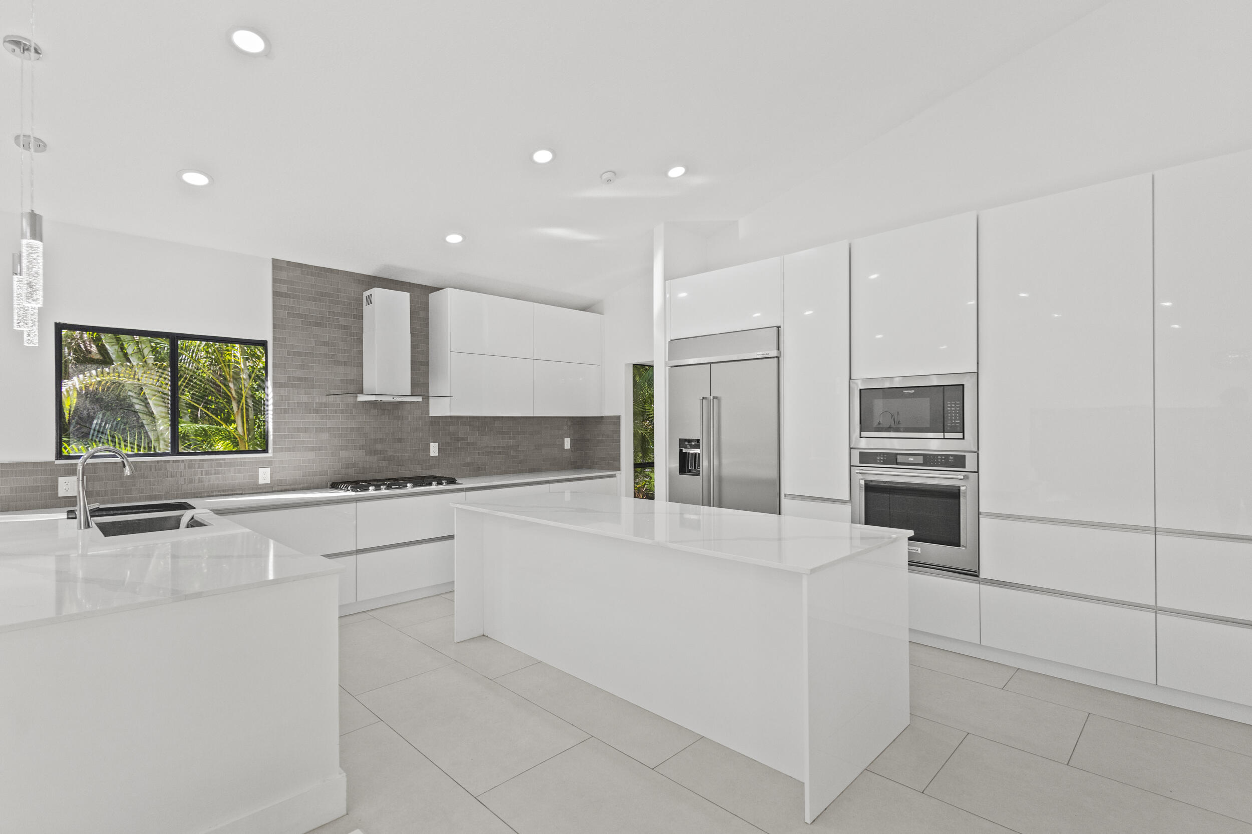 4798 Northwest 25th Way Boca Raton, FL 33434 - Photo 9 of 41 a large white kitchen with stainless steel appliances kitchen island granite countertop a refrigerator and a stove top oven