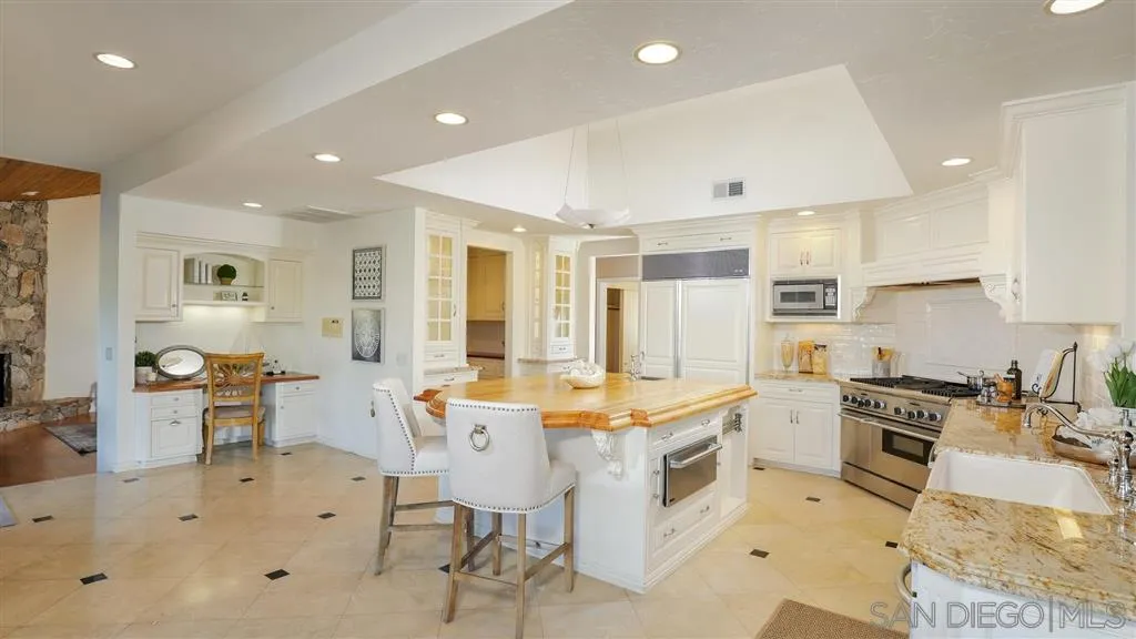 2723 Rich Lynn Ridge Road Escondido, CA 92025 - Photo 3 of 24 a large white kitchen with stainless steel appliances granite countertop a stove a sink a dining table and chairs