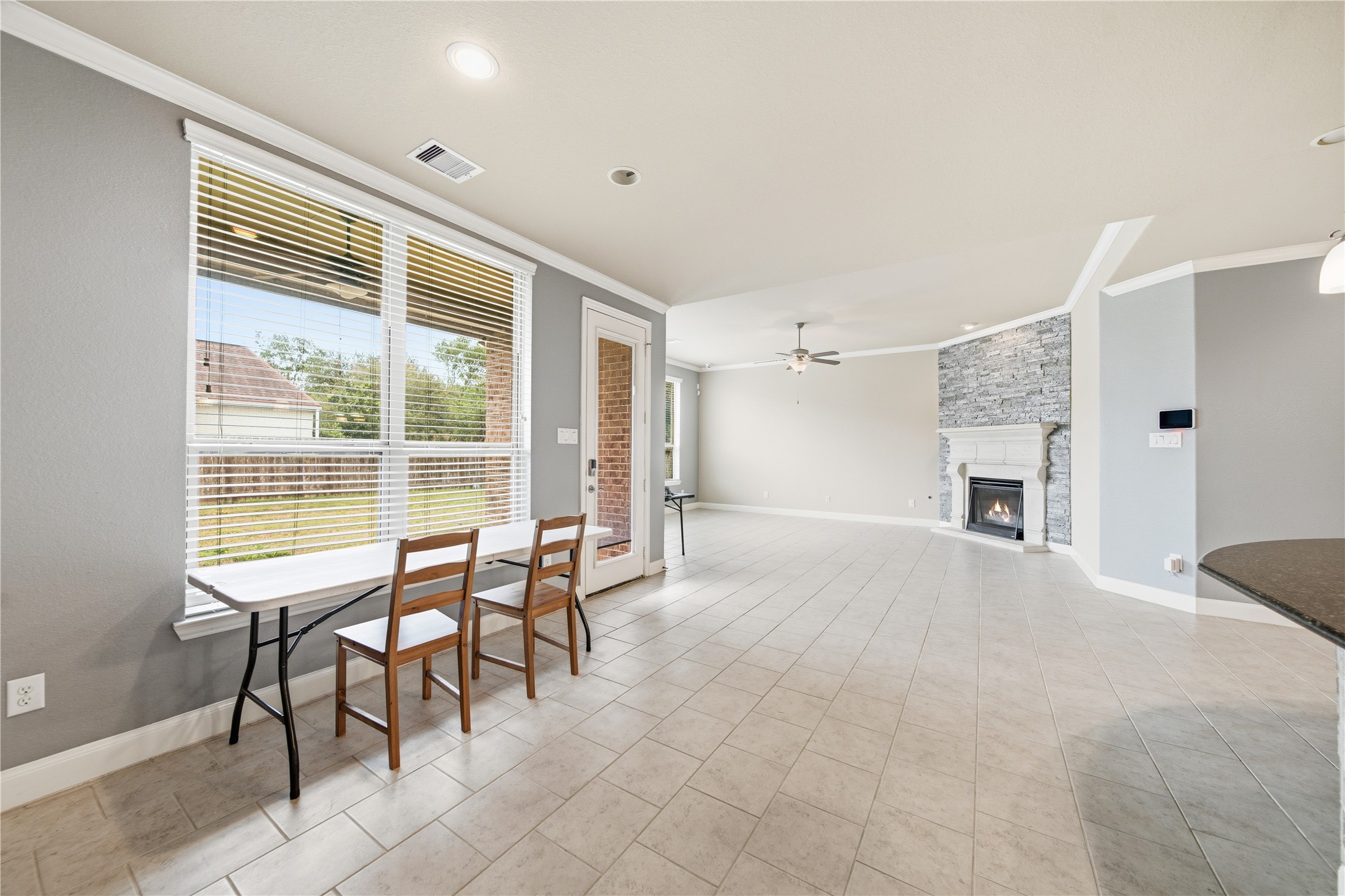 5303 Mesquite Willow Lane Rosharon, TX 77583 - Photo 10 of 32 This living area features a tiled floor, large windows for natural light, a cozy stone fireplace, and an open layout with a dining nook. Ideal for comfortable living and entertaining.