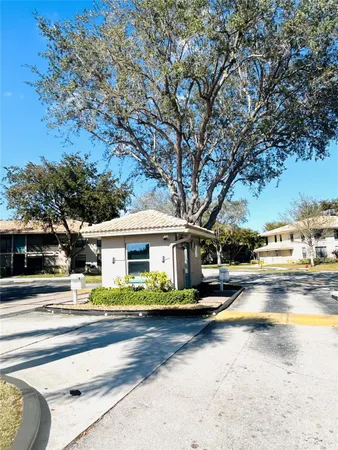 a view of a white house with a swimming pool and a lawn chairs under a large tree