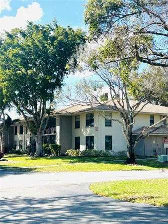 a view of a white house with a large trees