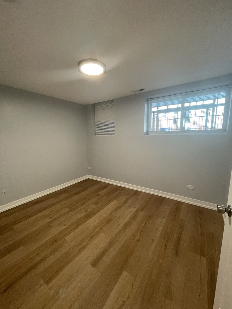 1024 West Ainslie Street, Unit 1 Chicago, IL 60640 - Photo 14 of 16 a view of empty room with wooden floor and fan