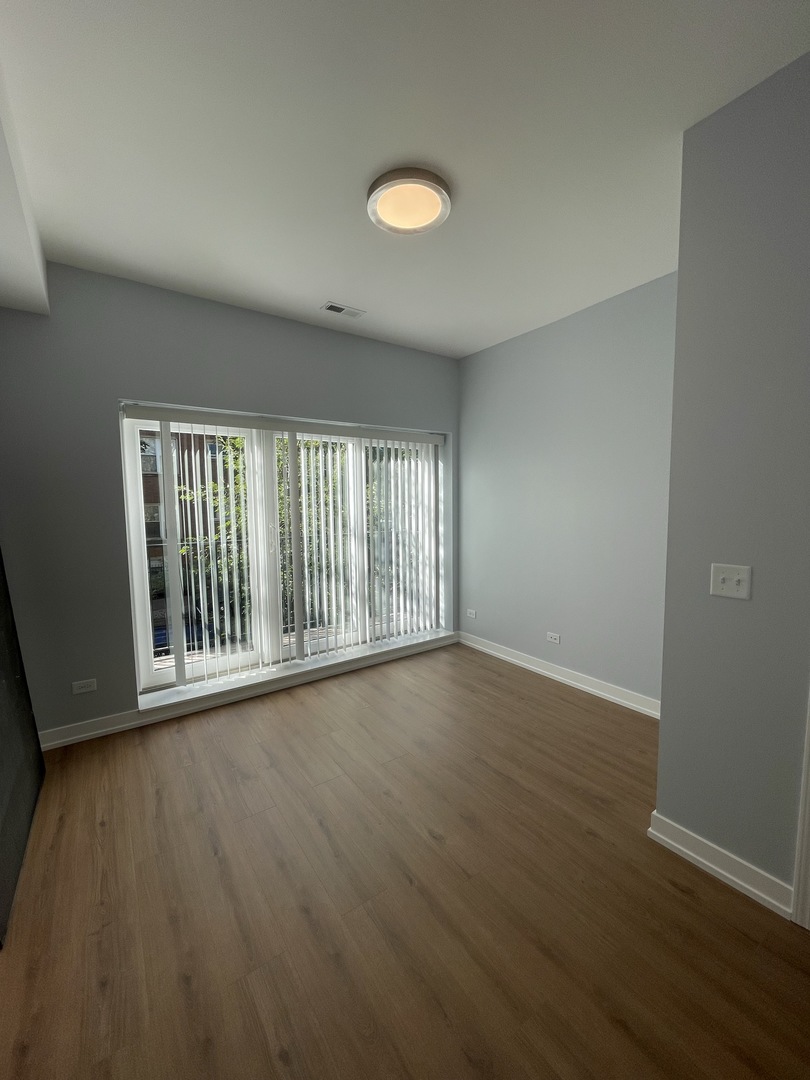 1024 West Ainslie Street, Unit 1 Chicago, IL 60640 - Photo 3 of 16 a view of an empty room with wooden floor and a window