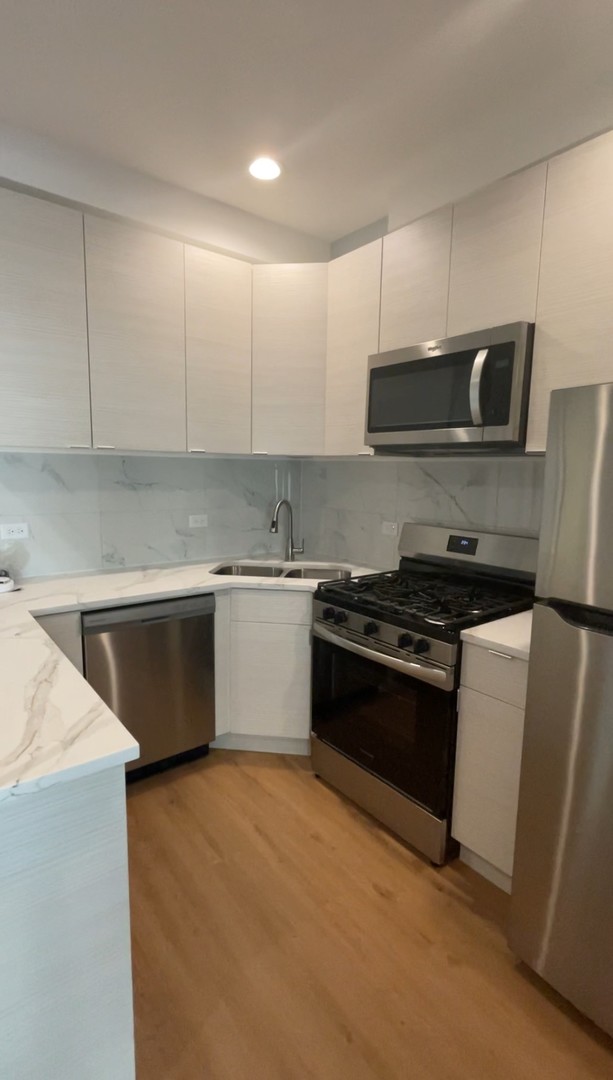 1024 West Ainslie Street, Unit 1 Chicago, IL 60640 - Photo 7 of 16 a kitchen with stainless steel appliances and white cabinets