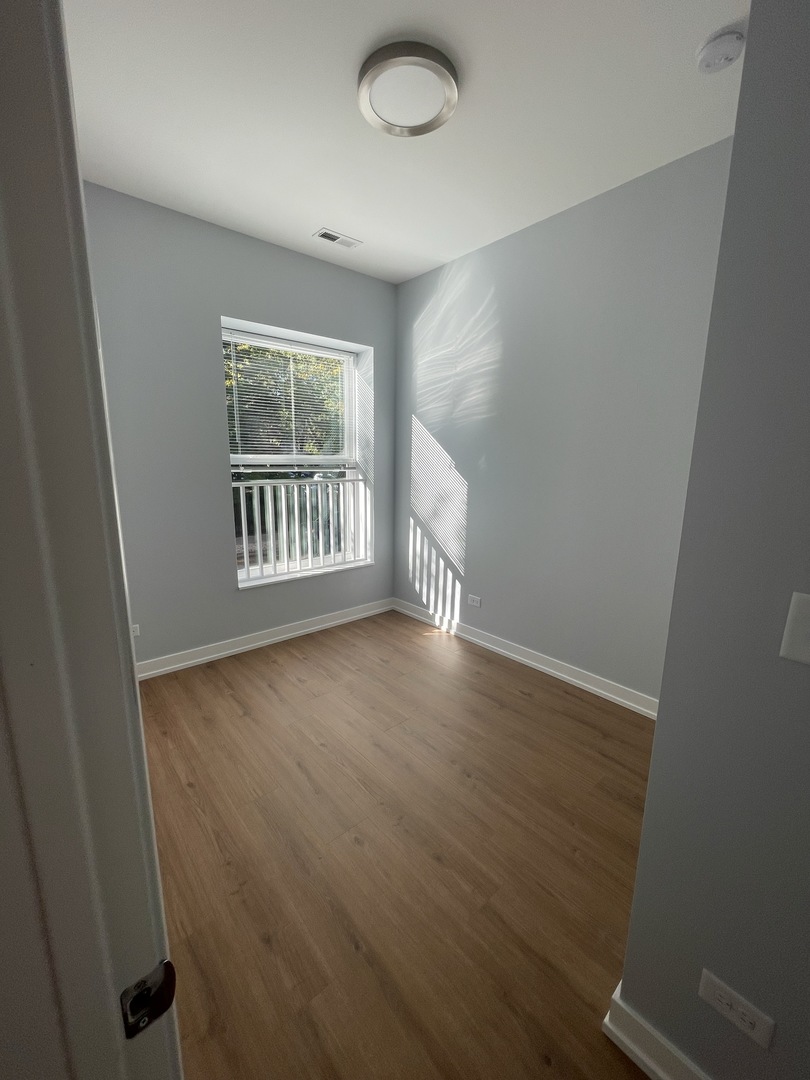 1024 West Ainslie Street, Unit 1 Chicago, IL 60640 - Photo 10 of 16 an empty room with wooden floor and windows