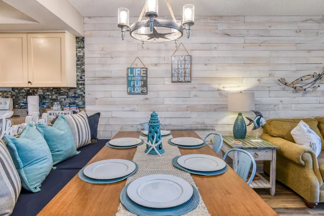 a dining room with wooden floor a chandelier a glass table and chairs