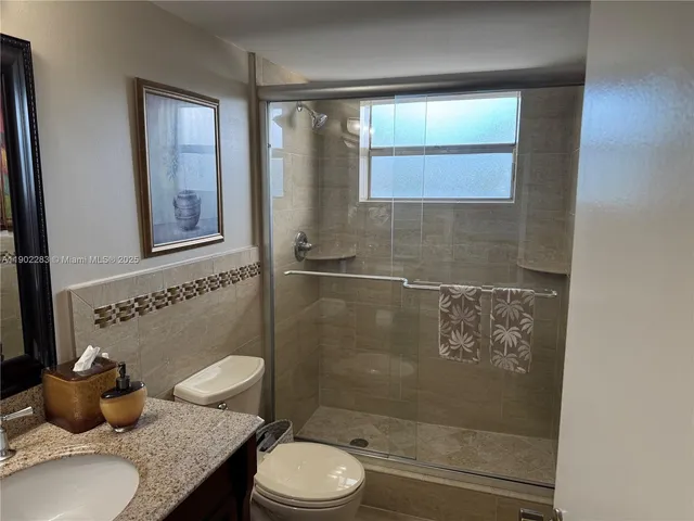 a bathroom with a granite countertop sink a toilet and shower