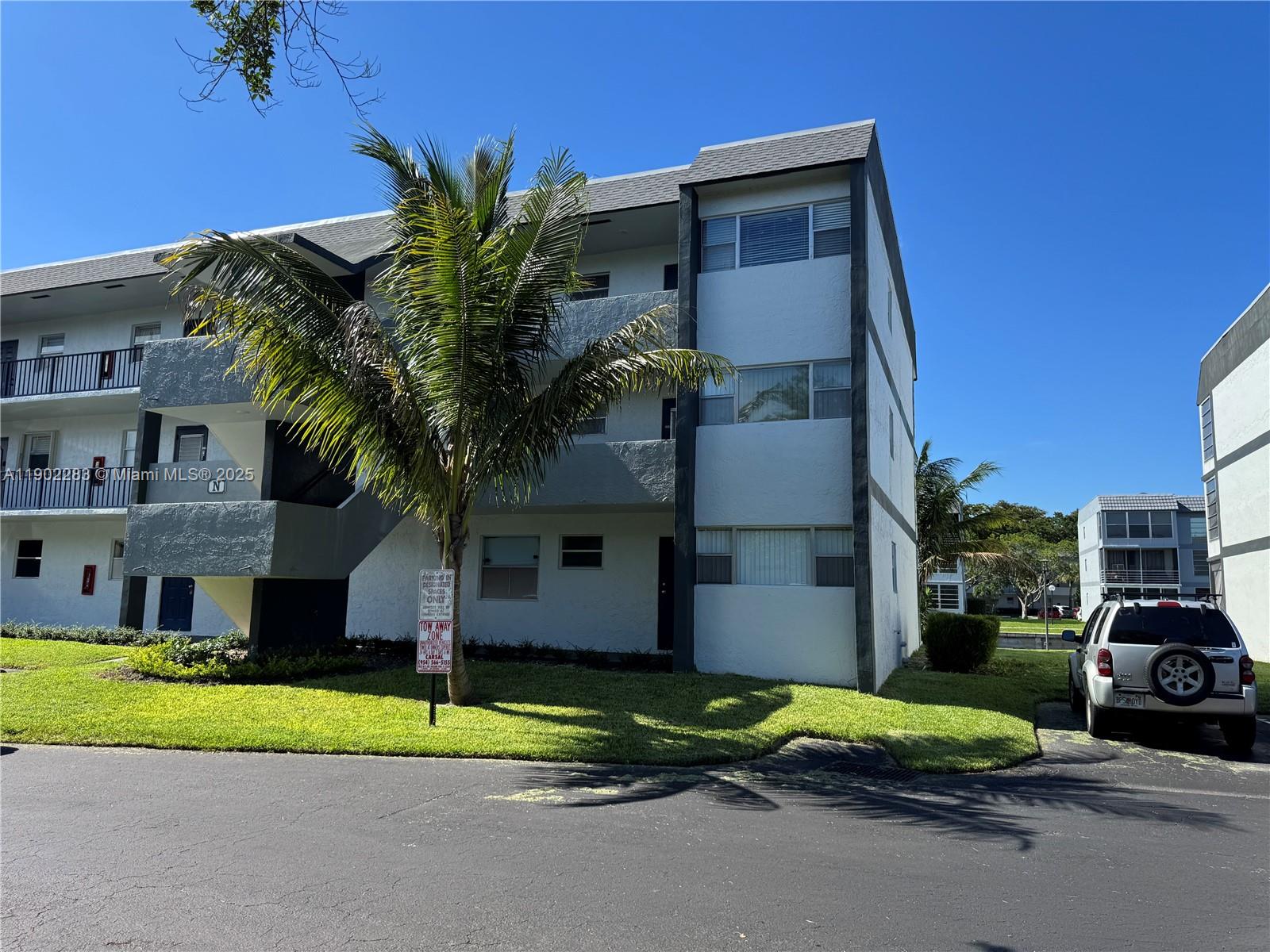 8330 Sands Point Boulevard, Unit N208 Tamarac, FL 33321 - Photo 27 of 35 a front view of a house with a yard and garage