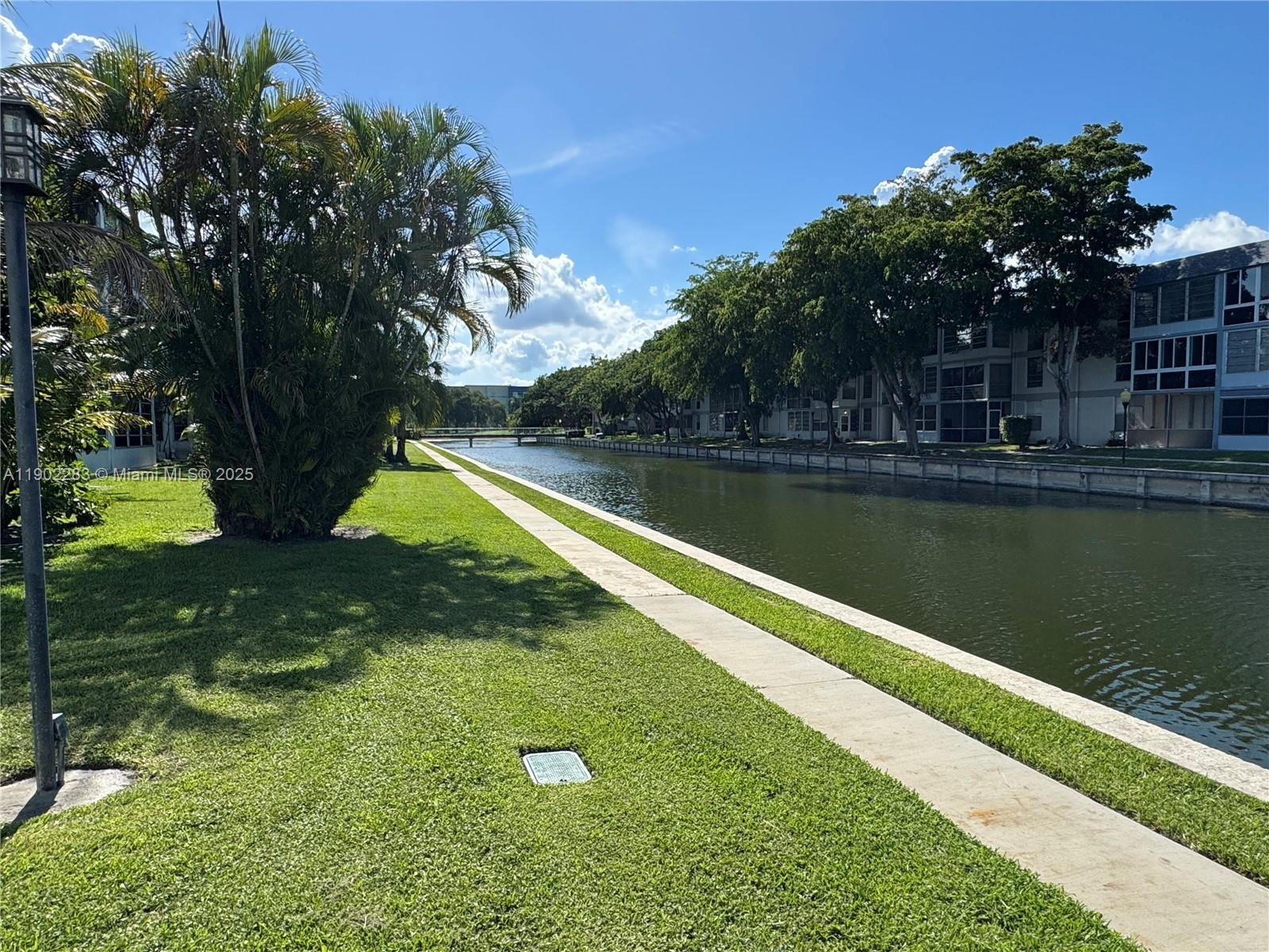 8330 Sands Point Boulevard, Unit N208 Tamarac, FL 33321 - Photo 28 of 35 a view of a swimming pool with a yard and large trees