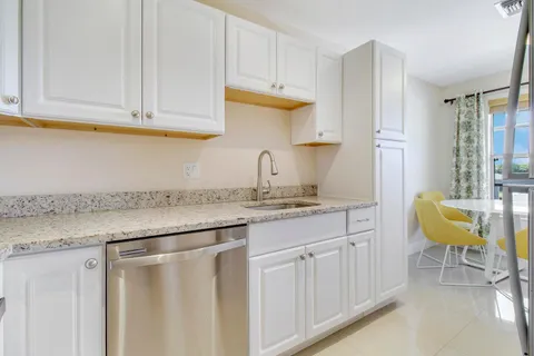a kitchen with stainless steel appliances granite countertop a sink a stove a dining table and chairs
