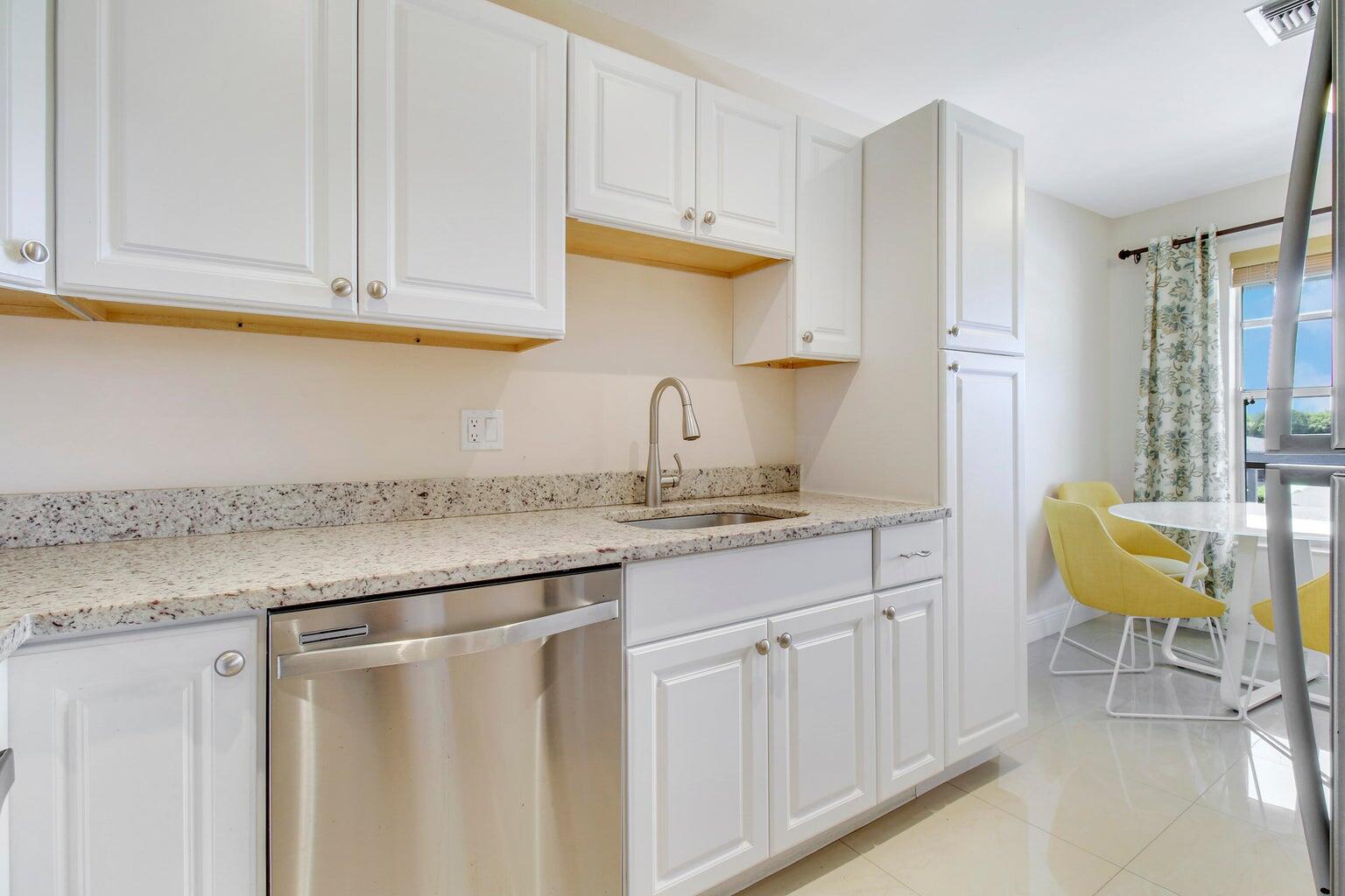 2730 Southwest 13th Street, Unit 203 Delray Beach, FL 33445 - Photo 6 of 23 a kitchen with stainless steel appliances granite countertop a sink a stove a dining table and chairs