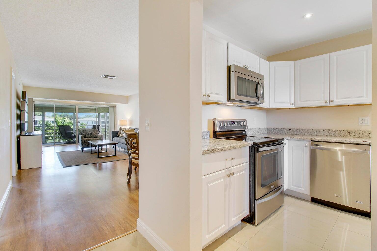 2730 Southwest 13th Street, Unit 203 Delray Beach, FL 33445 - Photo 8 of 23 a kitchen with white cabinets and stainless steel appliances