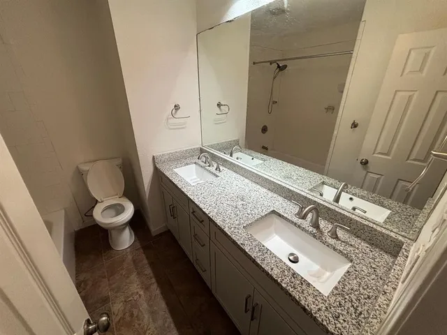 a bathroom with a granite countertop sink a toilet and a mirror