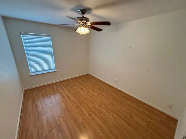 a view of an empty room with wooden floor and a chandelier fan
