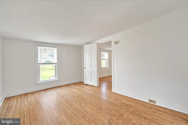 an empty room with wooden floor and window