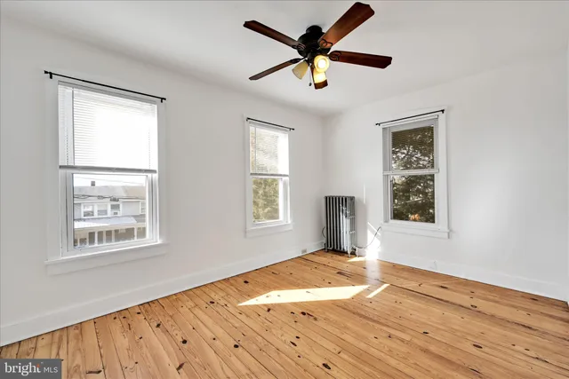 a view of empty room with wooden floor and fan