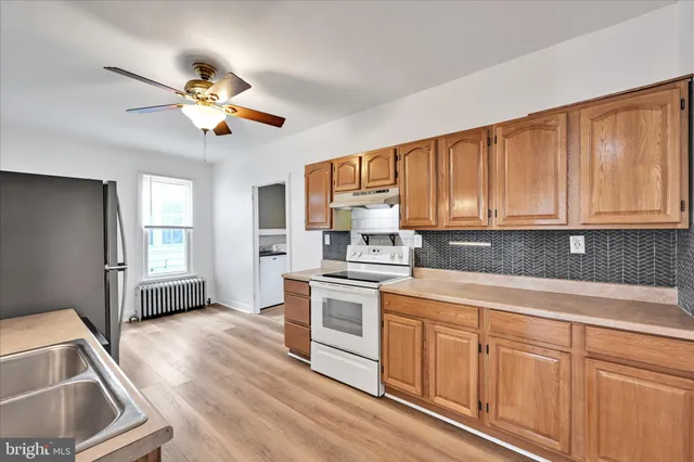 a kitchen with stainless steel appliances granite countertop a stove a sink dishwasher and white cabinets with wooden floor