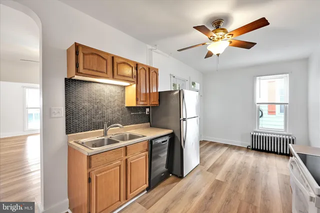 a kitchen that has a lot of cabinets stainless steel appliances and a large window