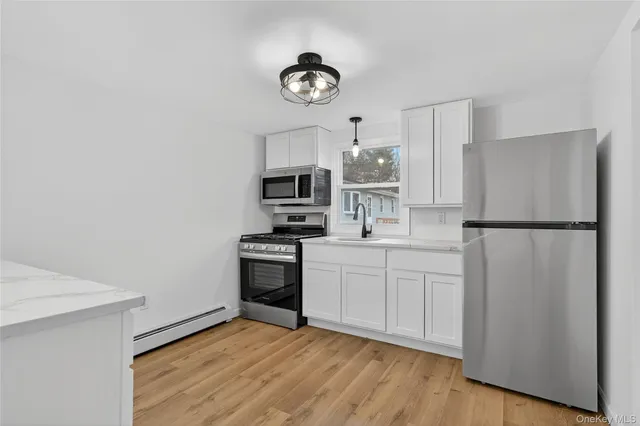 a kitchen with cabinets stainless steel appliances and wooden floor