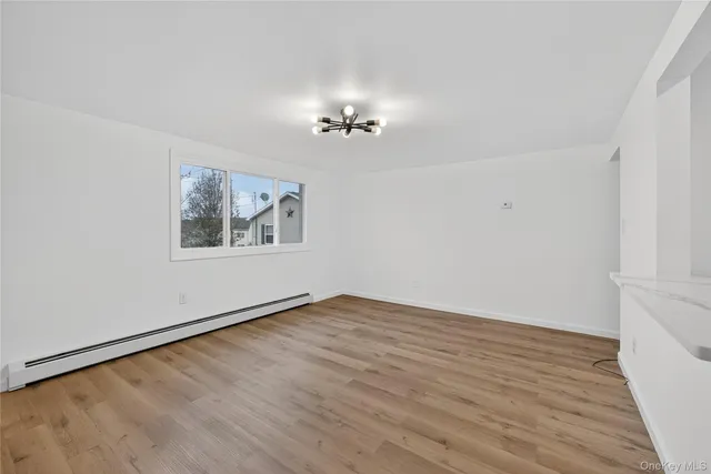 an empty room with wooden floor chandelier fan and windows