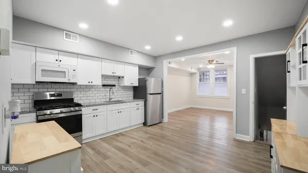 a kitchen with stainless steel appliances granite countertop a refrigerator a stove top oven a sink and dishwasher with wooden floor