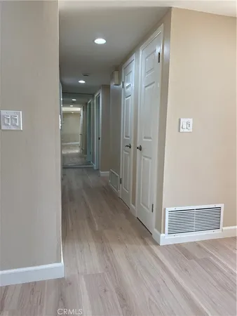 a view of an empty room with wooden floor and a ceiling fan