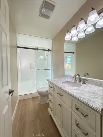 an empty room with kitchen view and wooden floor