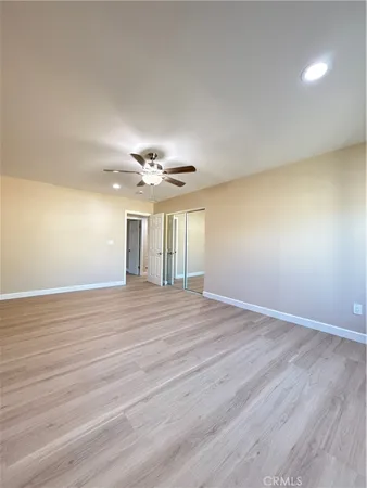 a view of an empty room with glass door and a chandelier fan