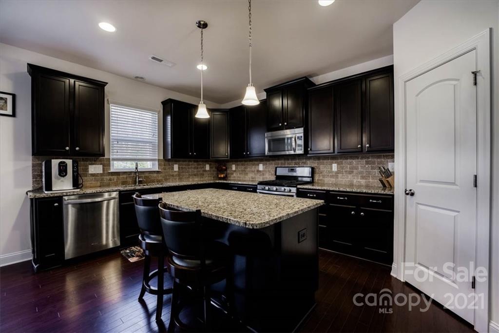 4008 Fallondale Road Waxhaw, NC 28173 - Photo 14 of 44 a kitchen with kitchen island granite countertop stainless steel appliances and wooden cabinets
