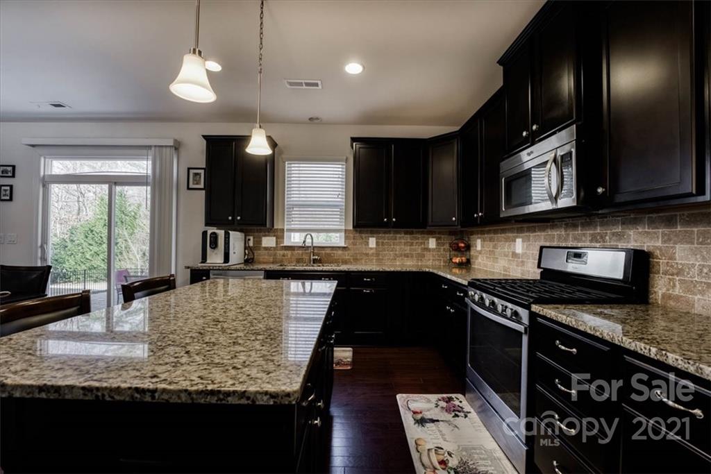 4008 Fallondale Road Waxhaw, NC 28173 - Photo 15 of 44 a kitchen with stainless steel appliances granite countertop wooden cabinets a stove top oven a sink and dishwasher