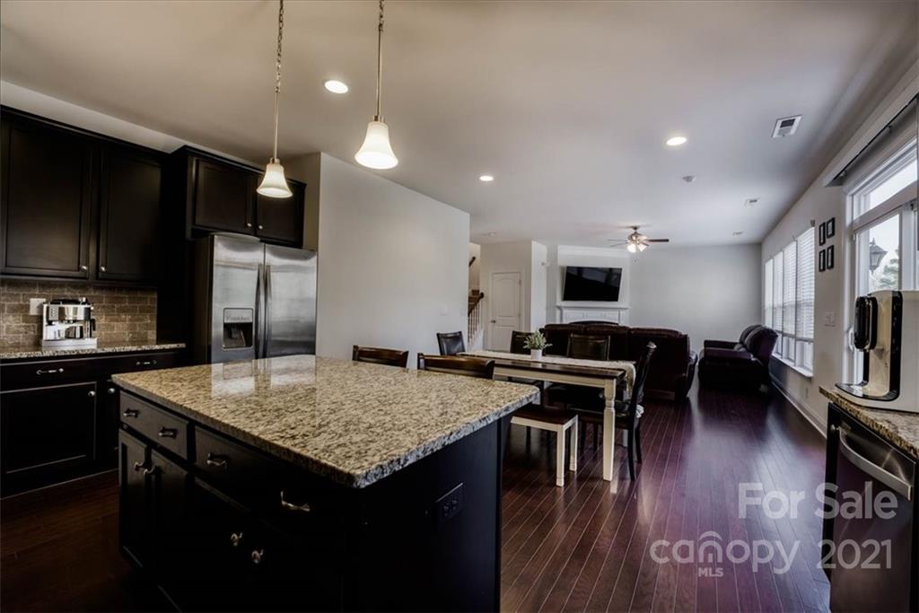 4008 Fallondale Road Waxhaw, NC 28173 - Photo 16 of 44 a kitchen with stainless steel appliances granite countertop a stove top oven a sink dishwasher a dining table and chairs with wooden floor