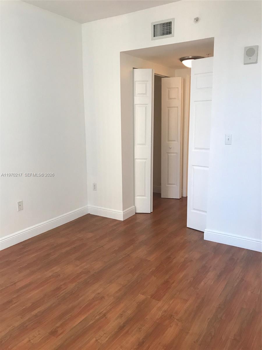2030 Douglas Road, Unit 708 Coral Gables, FL 33134 - Photo 6 of 8 an empty room with wooden floor and windows