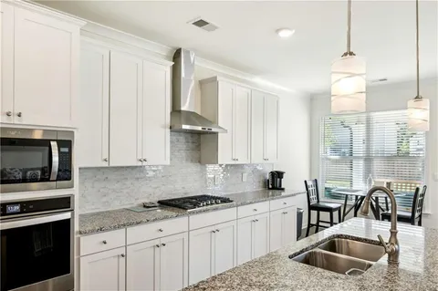 a kitchen with granite countertop a sink a counter top space appliances and cabinets