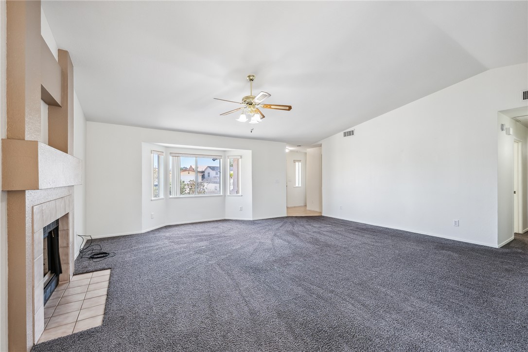 2524 South Ridge Avenue Bullhead City, AZ 86429 - Photo 14 of 64 Unfurnished living room with a ceiling fan, a fireplace, light carpet, baseboards, and vaulted ceiling