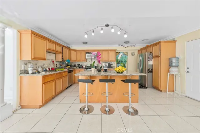 a dining hall with stainless steel appliances kitchen island granite countertop a table and chairs in it