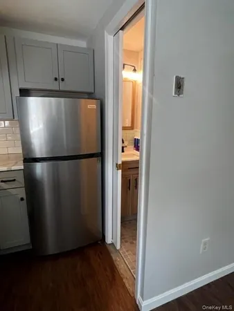 a view of a refrigerator in kitchen and an empty room
