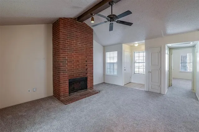a view of an empty room with a fireplace and a window