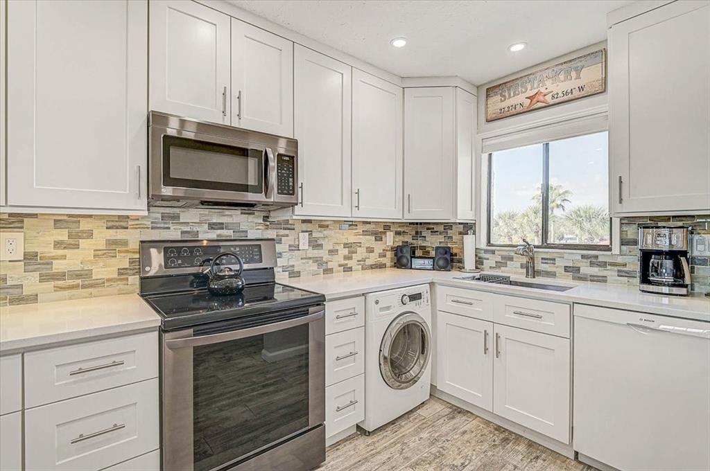 1624 Stickney Point Road, Unit 1624301 Sarasota, FL 34231 - Photo 10 of 55 a kitchen with white cabinets sink and stainless steel appliances