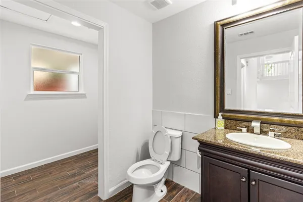 a bathroom with a granite countertop toilet sink and mirror