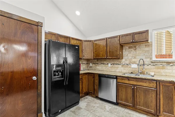 a kitchen with stainless steel appliances granite countertop a refrigerator and a sink