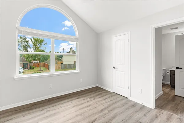 an empty room with wooden floor and windows