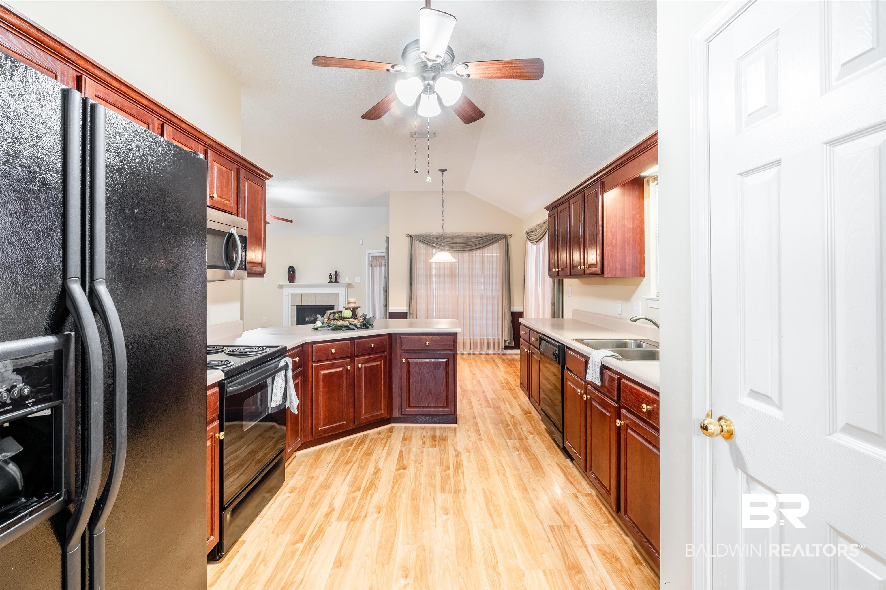 1784 Harrington Way Mobile, AL 36695 - Photo 8 of 18 Kitchen with ceiling fan, lofted ceiling, light hardwood / wood-style flooring, a tiled fireplace, and black appliances