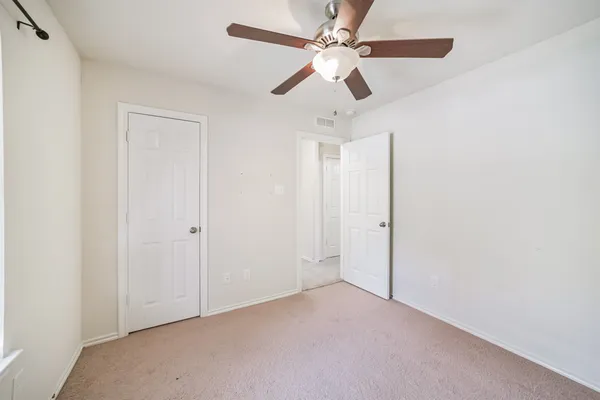 an empty room with a chandelier fan and a ceiling fan