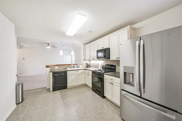 a kitchen with stainless steel appliances granite countertop white cabinets a sink dishwasher and a stove