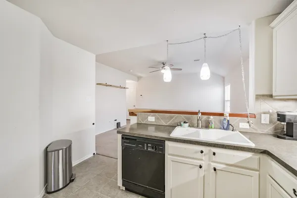 a kitchen with granite countertop a refrigerator stove and white cabinets