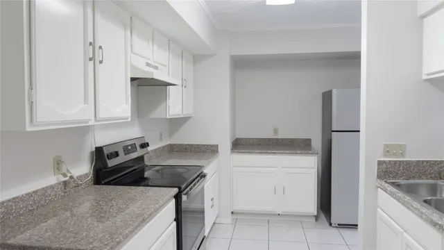 a kitchen with granite countertop a sink stove and refrigerator