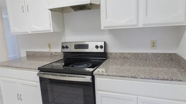 a kitchen with granite countertop white cabinets and a stove