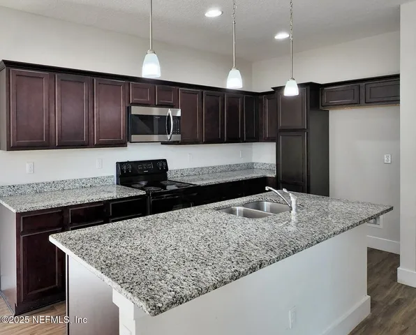a kitchen with stainless steel appliances granite countertop a sink refrigerator and microwave