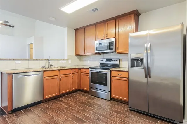 a kitchen with stainless steel appliances granite countertop a refrigerator stove microwave and sink