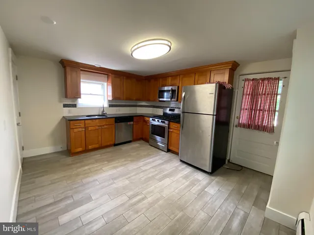 a kitchen with stainless steel appliances granite countertop a refrigerator a sink dishwasher a stove with wooden floors